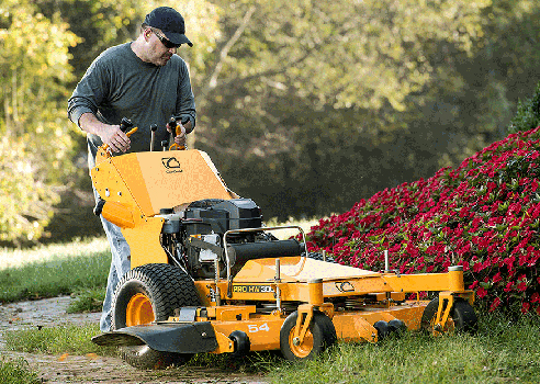 man cutting around flower bed with commercial walk-behind mower