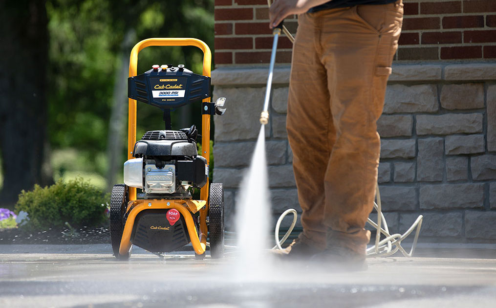 man using power washer on driveway
