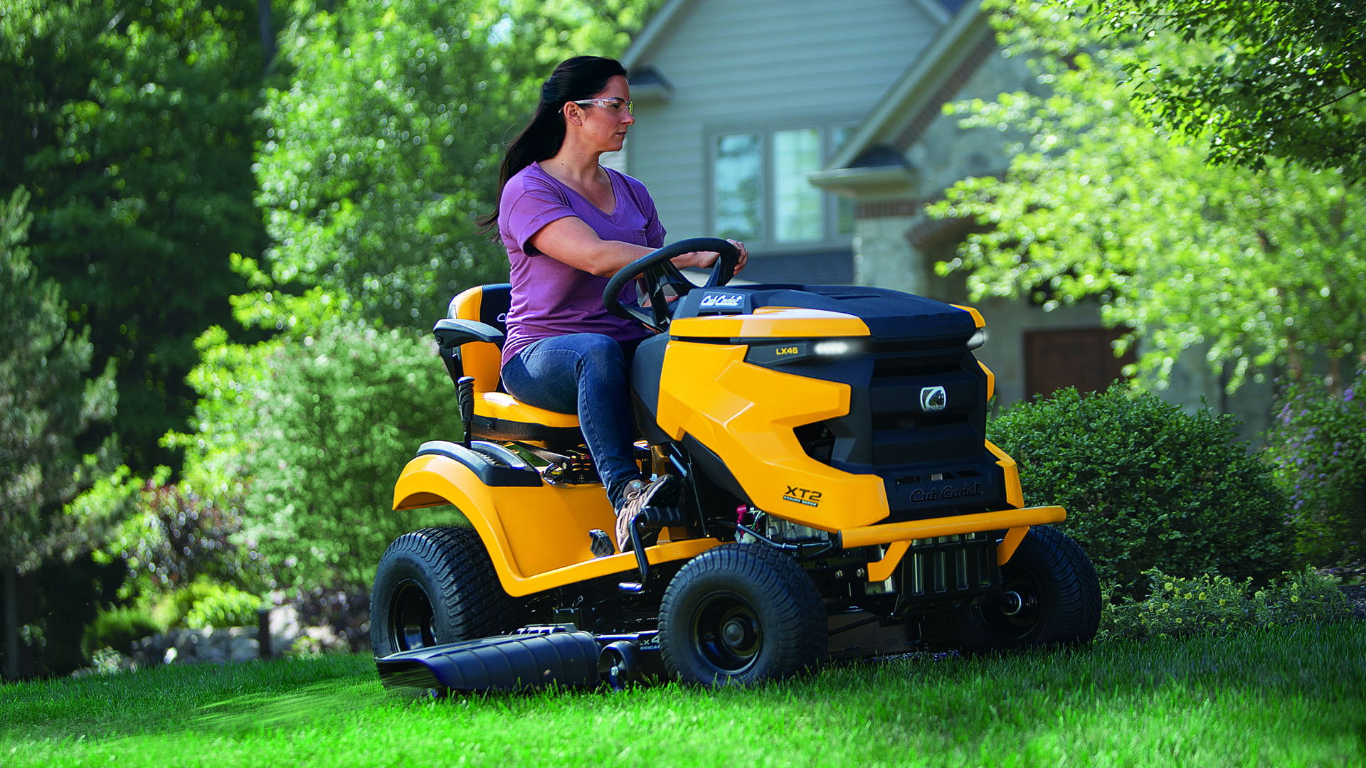 woman mowing her front yard with a cub cadet xt2 lawn tractor