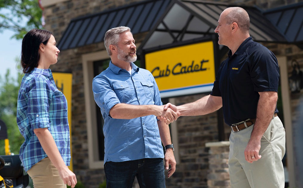 man shaking hands with salesman in front of store building