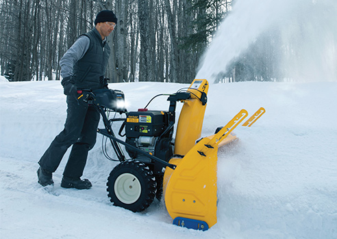 man pushing three stage snow blower