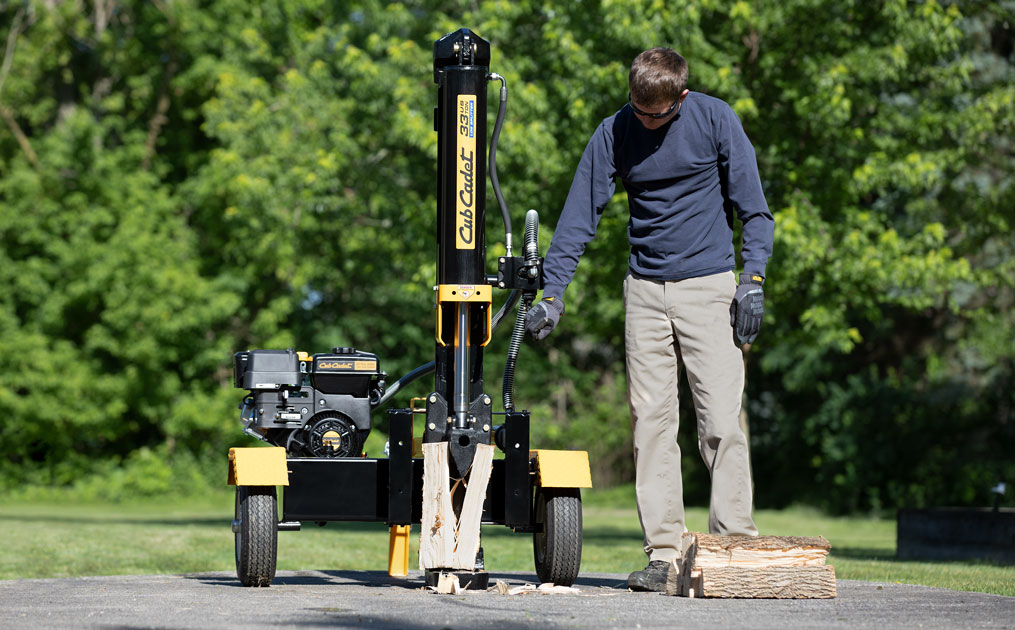 man using log splitter on a piece of wood