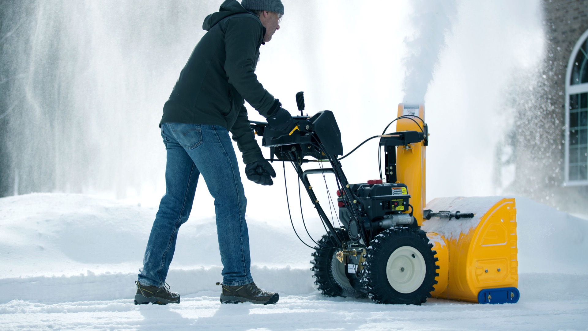 man snow blowing his driving and adjusting the angle of the chute