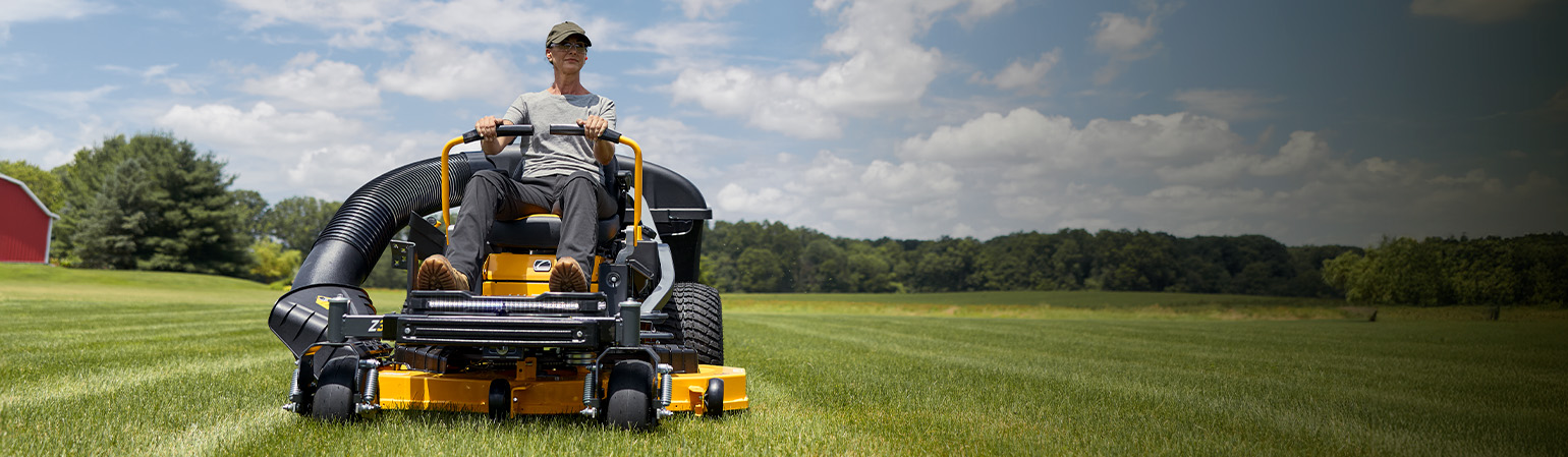 woman on cub cadet zero-turn mower cutting grass