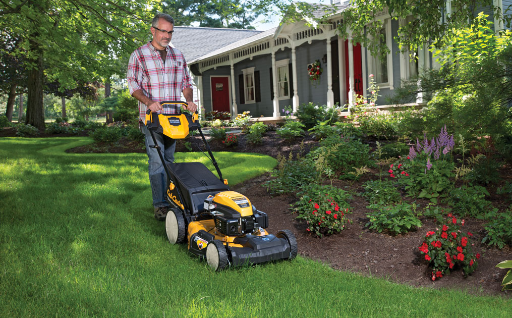 man cutting his lawn with walk-behind mower