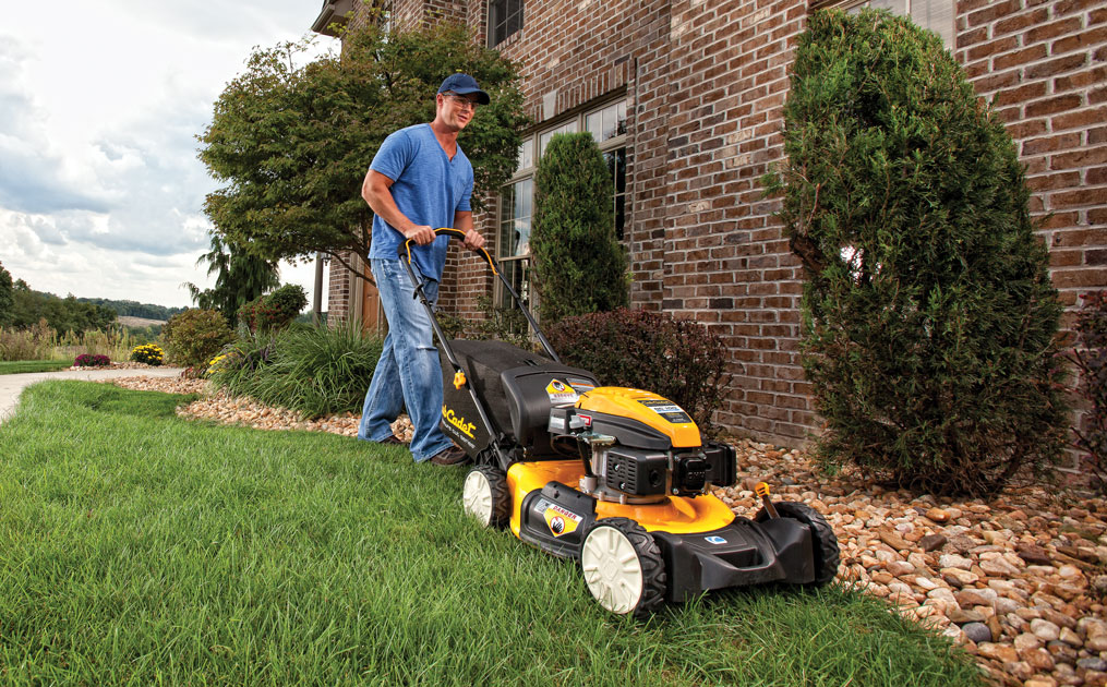 man cutting his lawn with walk-behind mower