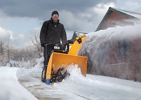 man pushing two stage snow blower