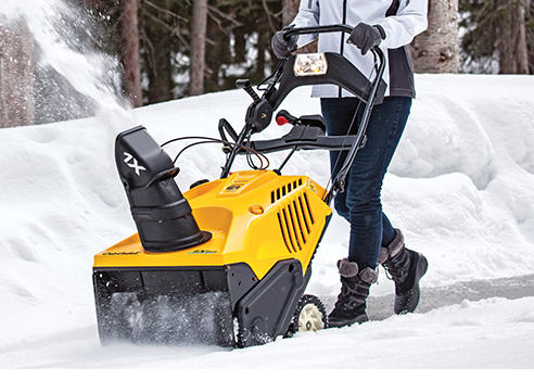 woman pushing single stage snow blower