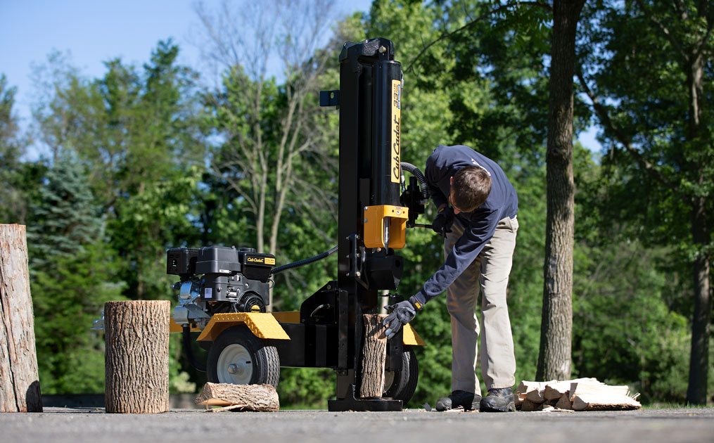 Man using log splitter in wooded area
