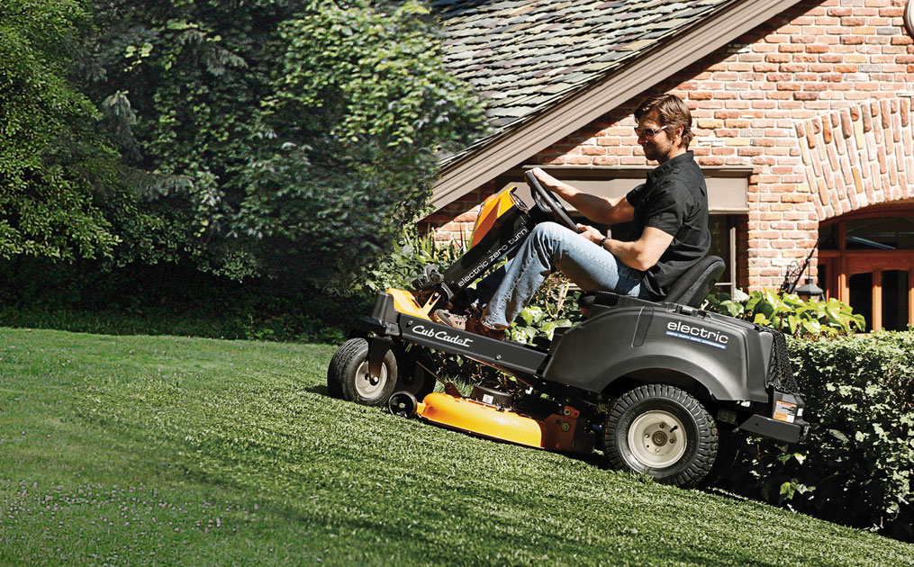 man on electric riding lawn mower cutting his yard